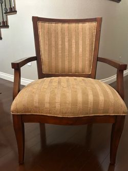 Tone-on-tone gold fabric and honey brown wooden chair.