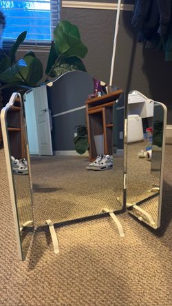 white vintage tri-fold mirror features beveled glass edges and adjustable hinged panels for versatile viewing angles.