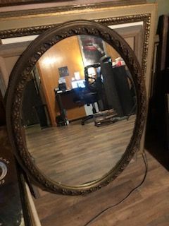 This is a vintage oval mirror with an ornate gold frame