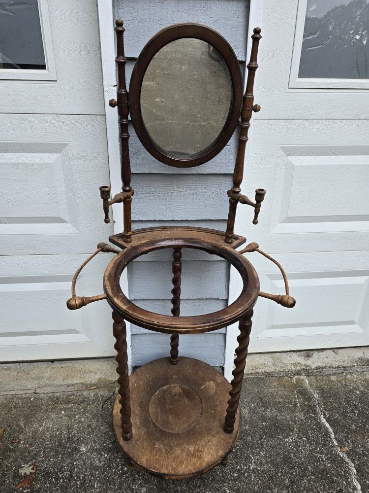 Antique Victorian wooden washstand with an oval mirror, candle holders, and towel bars.