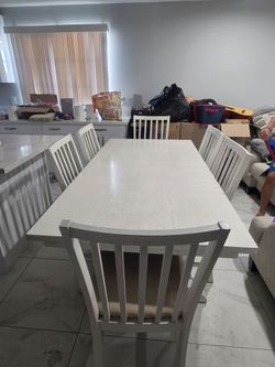 White solid wood extendable dining table with 6 chairs, seats 6 to 10.