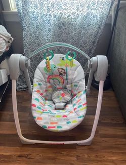 Infant swing with a colorful rainbow and animal-print seat, harness, overhead toy bar with hanging rings, everett Melvin Ave pick up area