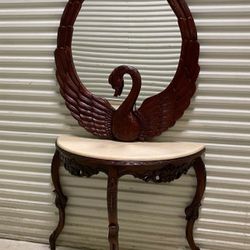 Hand carved Swan wall mirror features sculptural swan carving and a deep, matching table with marble top. 