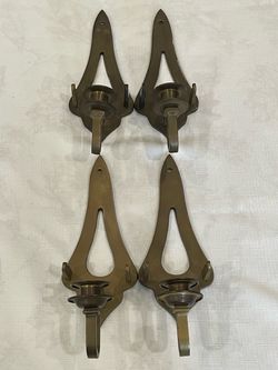 A set of four vintage brass wall-mounted candle sconces.