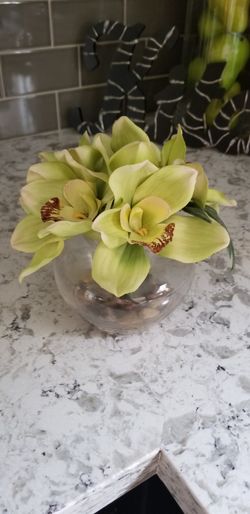 Faux floral - green flower in round clear glass vase