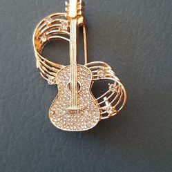 Guitar-shaped brooch with crystals.