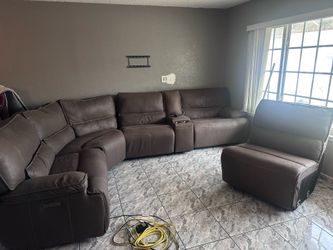 Spacious brown faux leather sectional sofa has power reclining seats and a center console with two cup holders and storage. This modular piece is upho
