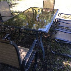 Hampton bay glass top table with a hole in the center for an umbrella with six rocking chairs