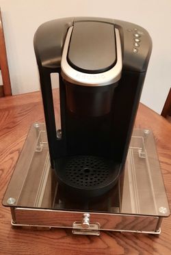 Keurig K-Select (or K80) single-serve K-Cup pod coffee maker, resting on a glass storage drawer base.