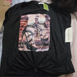 This black t-shirt with a high-heel graphic print is from the brand Occasion, as indicated by the tag attached to the shirt. It features a detailed im