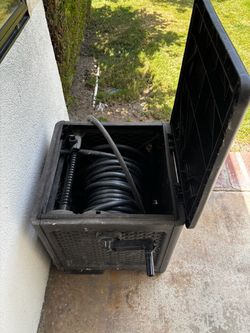 Suncast Swivel Smart Track  hose ( handle has tape)  with hose inside , working .