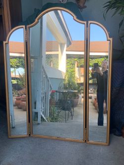 Vintage Hollywood Regency style gold-toned tri-fold vanity mirror.