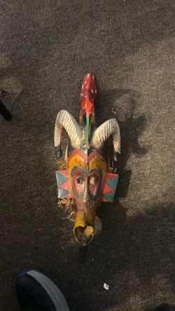 Guro mask from the Ivory Coast, decorated with animal horns and raffia.