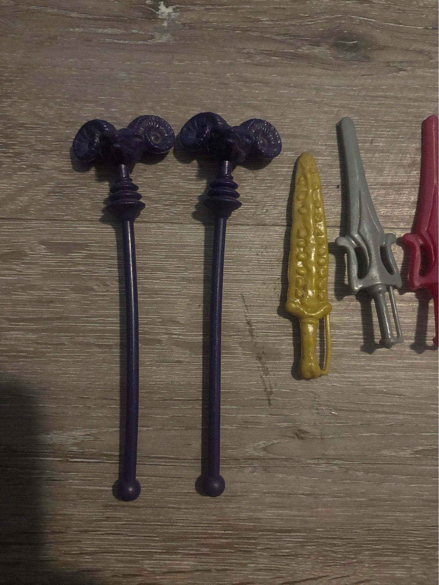 These are vintage weapon accessories from Mattel's He-Man Masters of the Universe (MOTU) toy line.