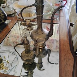 vintage brass ewers, also known as aftabas, which are traditional Indian or Middle Eastern pitchers or teapots. 