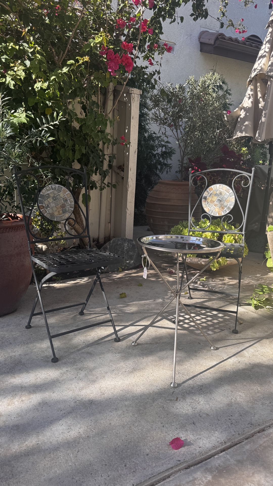 two rustic, metal bistro chairs with stainless steel folding table