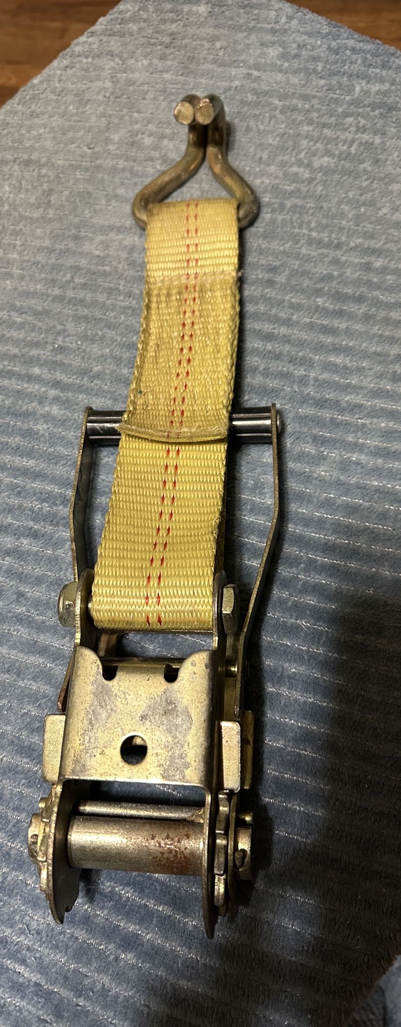 This is a ratchet tie-down strap with J-hooks, used for securing cargo on trailers or trucks.