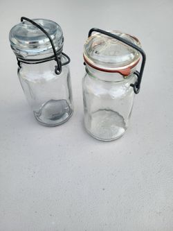 Clear glass vintage canning jars featuring wire bail closures, glass inserts/lids, and rubber gaskets, two jars
