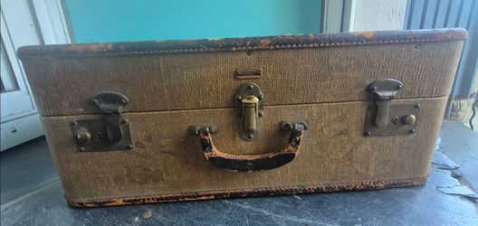 The selected region features a vintage Oshkosh canvas suitcase or travel trunk, typically dating back to the 1930s or 1940s.
This classic piece displa
