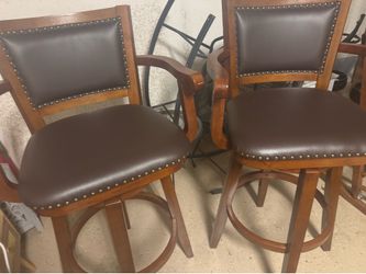 Pair of swivel bar stools with arms and nailhead trim