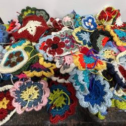 Large assortment of crochet granny squares. They are made of colorful acrylic yarn. There are approximately 100 small pieces, 50 blue/white, a finishe