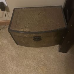 vintage brass-covered storage chest or trunk with an embossed floral motif.  It features an ornate, aged brass finish. The top has a curved, dome-top 