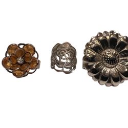 Set of three flower rings, sizes6.5, 7 & 9.25 two silver tone & one w/orange and rhinestone