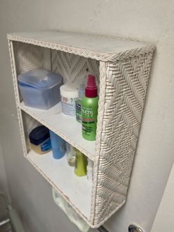 Mid-century white wicker wall shelf features a sturdy woven design for bathroom storage.