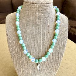 🍀 Pretty light green & iridescent, milky, white beaded necklace with silver tone crescent moon face charm pendant