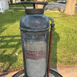 vintage Miller-Peerless fire extinguisher, likely from the 1920s, made of copper and brass. It is a hand-pump type water extinguisher, designed to be 