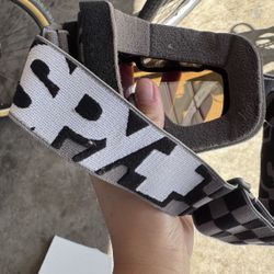 Spy Optic goggles with a checkered strap.