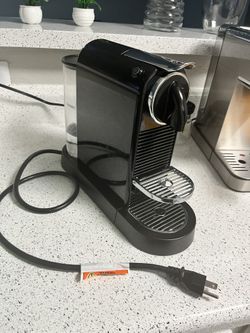 Nespresso coffee maker with milk frother next to it