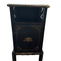 A Chinoiserie black lacquered cabinet with gold accents and bamboo motif.