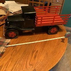 Pressed metal stake truck not sure how old does have one headlight missing, no rust, steering wheel intact, 4 tires roll, approximately 20” wi