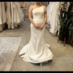 Romona Keveza Strapless gown made of silk crepe, features an asymmetrical neckline and a fluted skirt. 