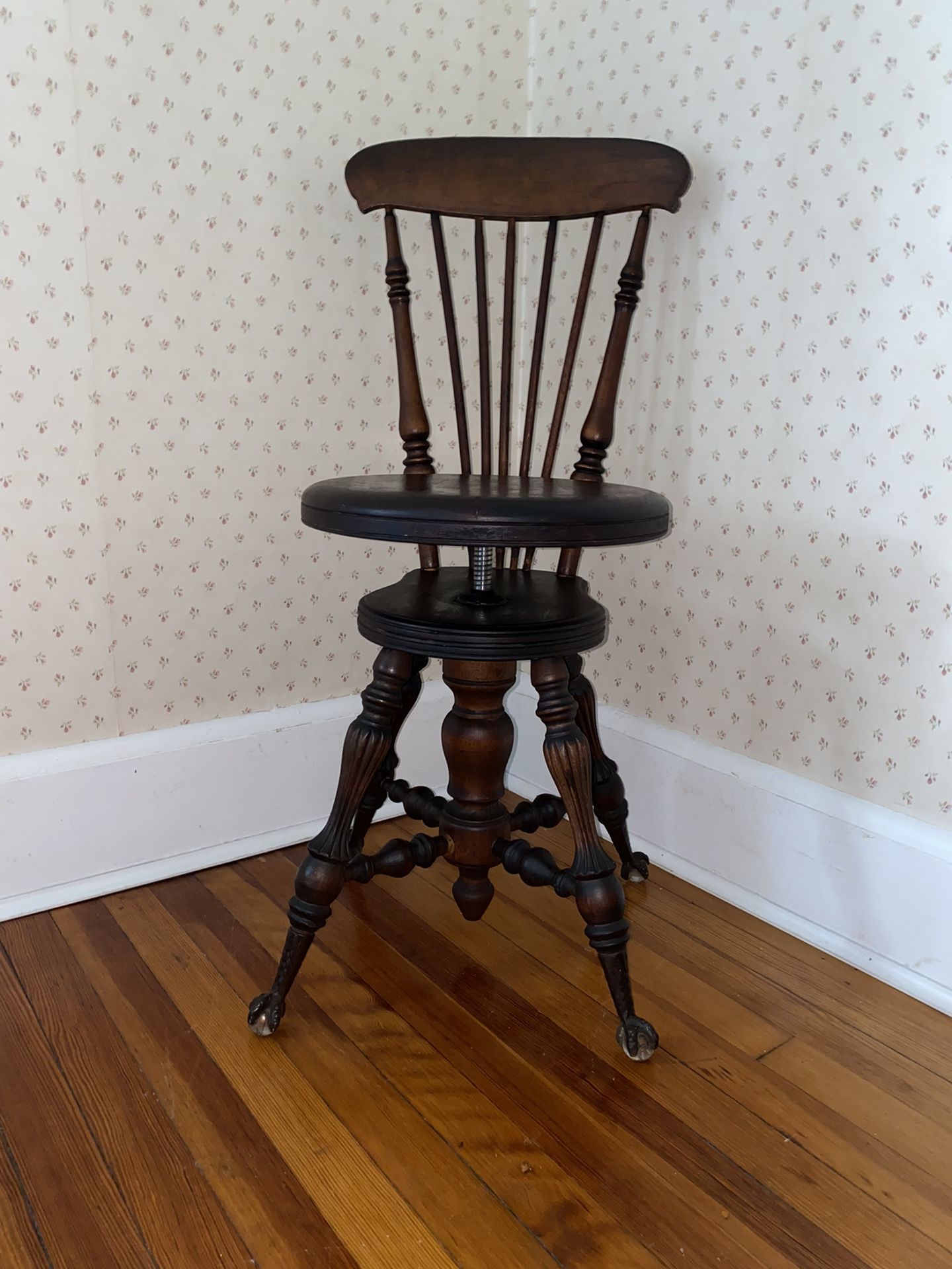 Antique 1890's, adjustable seat piano chair, with a spindle back on glass and claw feet.