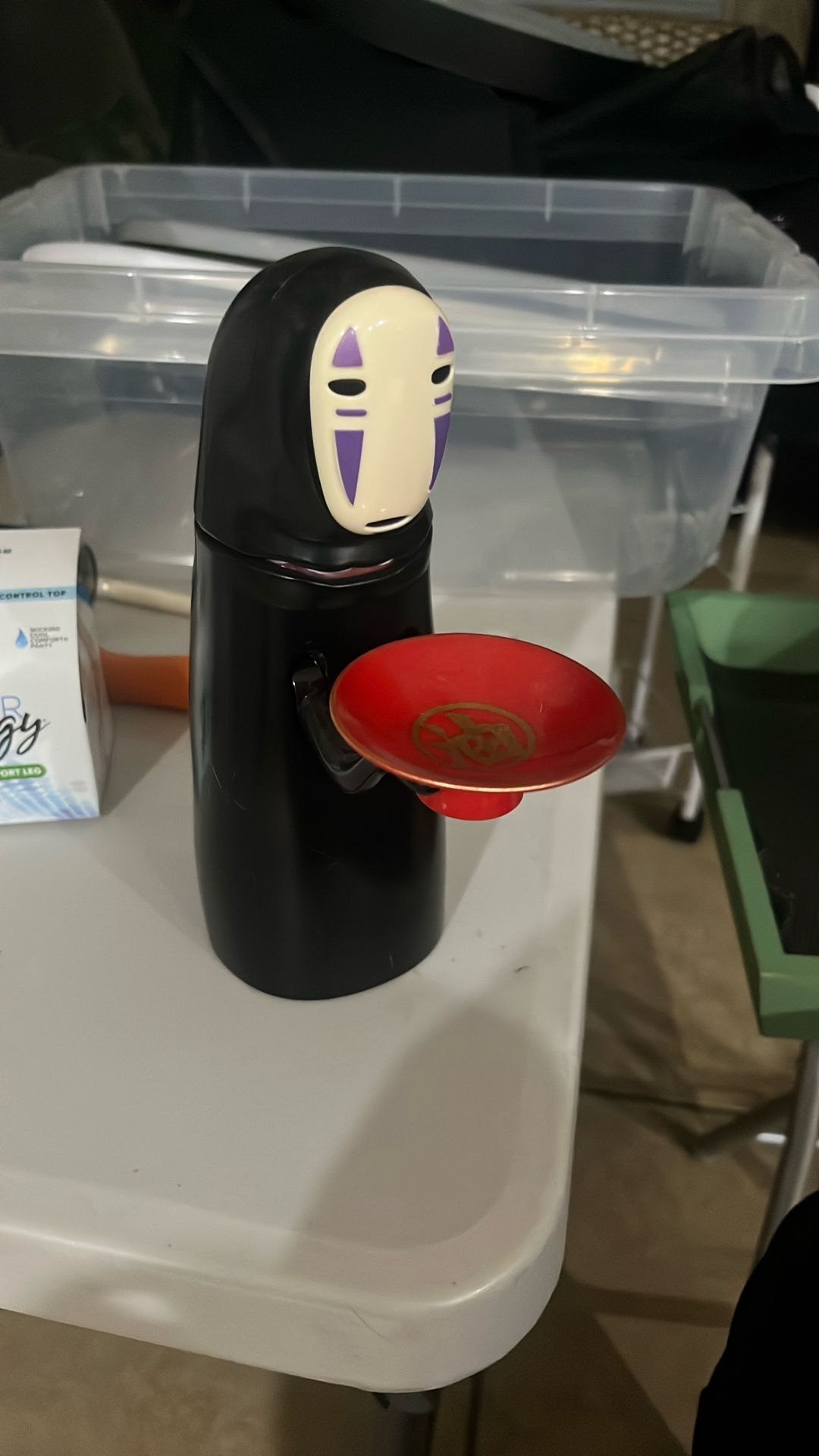 The object in the image is a No-Face (Kaonashi) coin bank from the Studio Ghibli film "Spirited Away". This unique piggy bank is designed to "eat" coi
