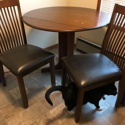 Round drop leaf wood(walnut) pedestal dining room table with 2 matching wood/upholstered chairs. It does have 2small “water Spots” on the top.p