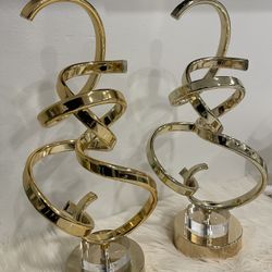 Two gold-finished aluminum modern abstract sculptures with a circular base