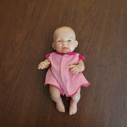Berenguer Happy Baby Girl Doll Plastic 9 " Pink Dress Toy. Weight 9 oz 
(plus shipping materials).  Pre-owned, good shape
