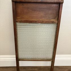 antique wooden washboard featuring a ribbed glass scrubbing surface nestled in a solid wood frame. 