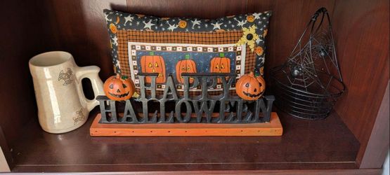 All for 25.00 Black cast iron-style 'Happy Halloween' tabletop sign on an orange wooden base, with two painted jack-o-lantern figures on each side.