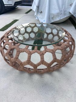 handwoven rope   coffee table with a thick round glass top.