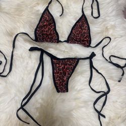 Two-piece string bikini with red leopard print panels. Black trim and long tie straps. Bold animal pattern. Lightweight and sexy look.  New small red 