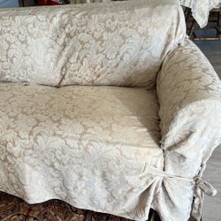  sofa slipcover with a damask or brocade pattern in a light beige or champagne color. 