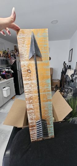 This rustic-style decorative wall sign features a distressed wood plank base paired with a black metal arrow detail.