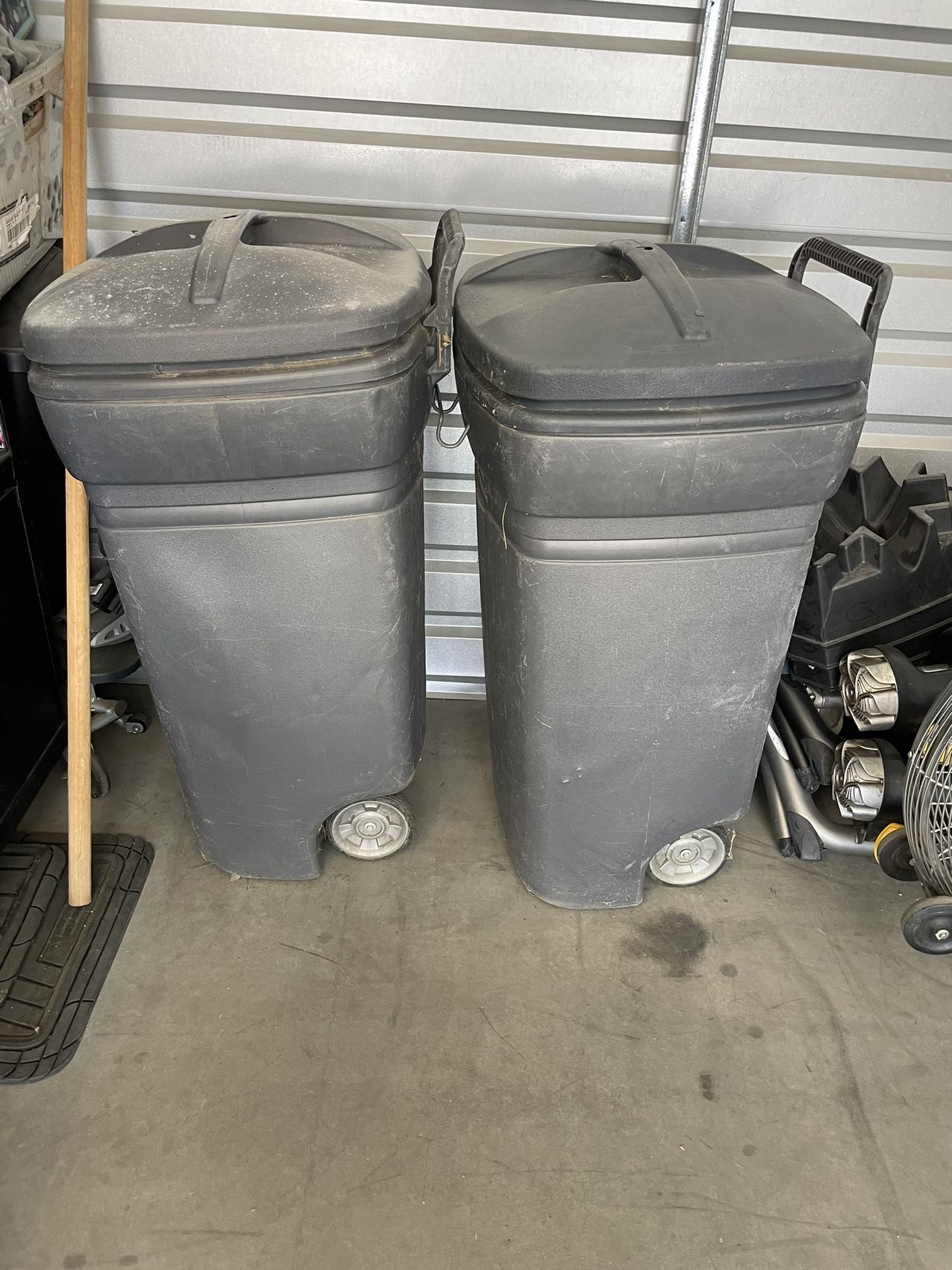 Two wheeled Rubbermaid garbage cans with lids