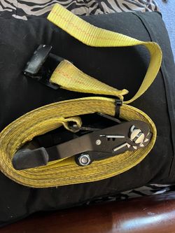 Heavy-duty yellow ratchet strap for securing loads.