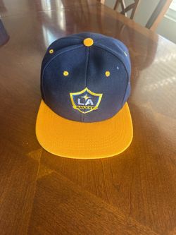 LA Galaxy fanatics batters box snapback hat features a navy crown with a contrasting yellow flat brim and embroidered team logo