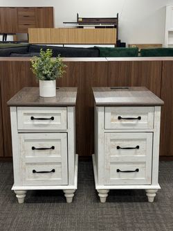 Set of 2, Farmhouse Nightstands with 3 drawers, rustic white distressed finish, brown wood top, and black handles. Built-in charging station with 2 AC